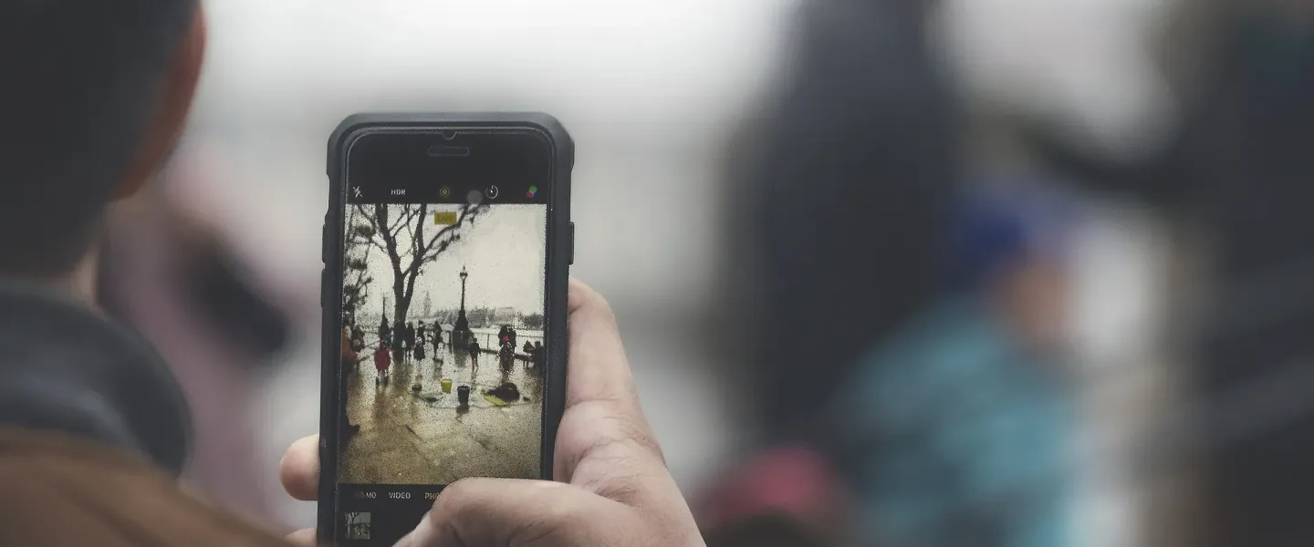 Person seen from behind taking a photo on a smartphone