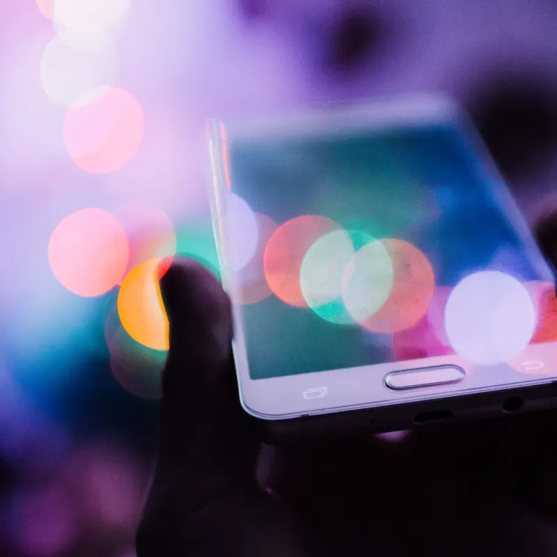 Smartphone held in hand against colourful bokeh lights